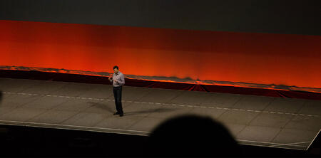 Dharmash Shah speaking on stage. 